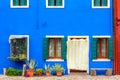 Blue colored house with flowers and bench. Colorful houses in Burano island near Venice, Italy. Venice postcard. Famous place for