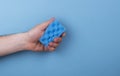 Blue colorful sponge for washing dishes in your hands on a blue background Royalty Free Stock Photo