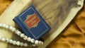 Hindu holy book and cowrie shell on a wooden surface with golden satin cloth