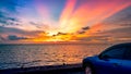 Blue compact SUV car with sport and modern design parked on concrete road by the sea at sunset. Road trip travel. Electric car Royalty Free Stock Photo