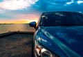 Blue compact SUV car with sport and modern design parked on concrete road by the sea at sunset. Environmentally friendly technolog Royalty Free Stock Photo