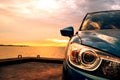 Blue compact SUV car with sport and modern design parked on concrete road by the sea at sunset. Environmentally friendly Royalty Free Stock Photo