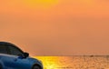 Blue compact SUV car with sport and modern design parked on concrete road by the sea at sunset. Environmentally friendly Royalty Free Stock Photo