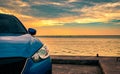 Blue compact SUV car with sport and modern design parked on concrete road by the sea at sunset in the evening. Hybrid and electric Royalty Free Stock Photo