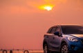 Blue compact SUV car with sport and modern design parked on concrete road by the sea at sunset in the evening. Hybrid and electric Royalty Free Stock Photo