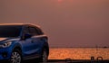 Blue compact SUV car with sport and modern design parked on concrete road by the sea at sunset in the evening. Hybrid and electric Royalty Free Stock Photo