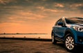 Blue compact SUV car with sport and modern design parked on concrete road by the sea at sunset in the evening. Hybrid and electric Royalty Free Stock Photo