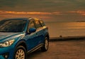 Blue compact SUV car with sport and modern design parked on concrete road by the sea at sunset in the evening. Hybrid and electric Royalty Free Stock Photo