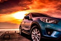 Blue compact SUV car with sport, modern, and luxury design parked on concrete road by the sea at sunset. Front view of beautiful Royalty Free Stock Photo