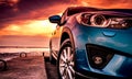 Blue compact SUV car with sport, modern, and luxury design parked on concrete road by the sea at sunset. Front view of beautiful