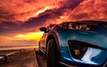 Blue compact SUV car with sport, modern, and luxury design parked on concrete road by the sea at sunset. Front view of beautiful h Royalty Free Stock Photo