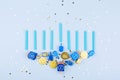 Blue confetti background with menora made of dreidels and chocolate coins. Hanukkah and judaic holiday concept. Royalty Free Stock Photo