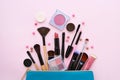 A blue cosmetics bag with makeup products spilling out on to a pastel pink background Royalty Free Stock Photo