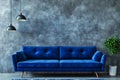 A blue couch sitting in front of a gray wall Royalty Free Stock Photo