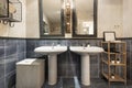 Blue and cream tiled cloakroom with twin sinks and black framed