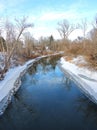 Blue creek water reflects blue sky above in winter Royalty Free Stock Photo