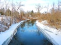 Blue creek water reflects blue sky above during wintertime Royalty Free Stock Photo