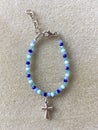 Blue Crystal Glass Beaded Bracelet with Cross Charm on Textured Background