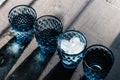 Blue crystal glasses of geometric pattern with ice and drinks in diagonal line and giving colorful shadows on black top