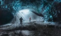 Blue crystal ice cave entrance with tourist climber and an underground river beneath the glacier located in the Royalty Free Stock Photo