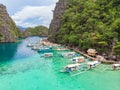 Blue crystal water in paradise Bay with boats on the wooden pier at Kayangan Lake in Coron island, Palawan, Philippines Royalty Free Stock Photo