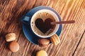 cup of coffee with heartshape foam and macaroons on the wooden background. Coffee is the good idea