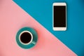 A blue cup with coffee and a mobile phone stands on a pink and blue background. Morning breakfast, business