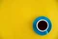 Blue cup of coffee stands on a yellow background. Morning breakfast, business