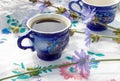 Blue cup of coffee tea chicory drink with chicory flower, hot beverage on embroidered fabric background