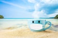 Blue cup of coffee on white sand beach over blue sky and sea on day noon light background.