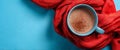 A blue cup filled with warm coffee sits on a bright blue surface. It is wrapped with a soft red scarf, creating a cozy and Royalty Free Stock Photo