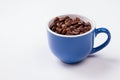 Blue cup full of coffee beans isolated on white. Royalty Free Stock Photo