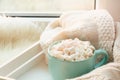 Blue cup of hot chocolate with marshmallow on windowsill with furskin for relax. Weekend concept. Home style.