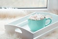 Blue cup of hot chocolate with marshmallow on windowsill with furskin for relax. Weekend concept. Home style.