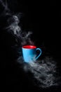 Blue Cup of hot coffee surrounded in steam black background Royalty Free Stock Photo