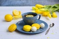 Blue cup of tea with lemon, yellow macarons, coconut cookies and tulips on a light background. Home relax Royalty Free Stock Photo