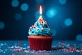 Blue cupcake, red sprinkles, and a lit candle on blue backdrop