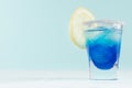 Blue curacao cocktail with lemon slice, ice cubes, sugar rim in shot glass on elegant white wood board and pastel mint color wall. Royalty Free Stock Photo
