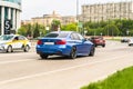 Blue 320d sedan F30 car moving on the street. Rear side view of BMW 3 Series auto driving on the road with city background Royalty Free Stock Photo