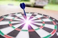 Blue dart arrow hitting in the target center of dartboard with g