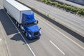 Blue day cab big rig semi truck with roof spoiler transporting cargo in dry van semi trailer driving on the divided highway road Royalty Free Stock Photo