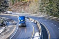 Blue day cab big rig semi truck with semi trailer transporting goods on winding wet winter snow road Royalty Free Stock Photo