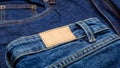 Blue denim jeans with emty label. Brown blank leather label tag on denim pants background. Blank mockup beige leather Royalty Free Stock Photo