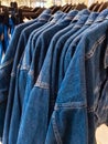 Blue denim jeans jackets hanging on rail at clothing store in mall. Sales retail consumerism fashion casual wear