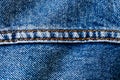 Blue denim jeans with middle brown yellow color sewing thread seam macro closeup textile background