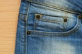Blue denim with seam, studs and Jeans pocket on wood Royalty Free Stock Photo