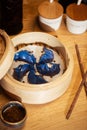 Blue Dim Sum chinese cuisine in bamboo steamer and pot. Top view fresh dumplings with hot steams on wood plate with Royalty Free Stock Photo