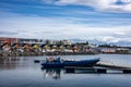 Blue dinghy boat moored in the Karsnes harbour, Iceland. Colorful cottages along the coastline in background. Royalty Free Stock Photo