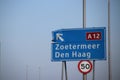 Blue direction sign on motorway A12 heading to Den Haag and Zoetermeer in the Netherlands