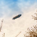 Blue dirigible flying in cloudy sky Royalty Free Stock Photo